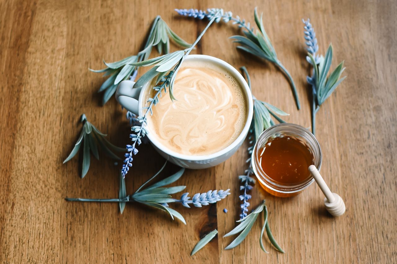 Top view of coffee with honey and lavender on wooden table, creating a soothing ambiance.